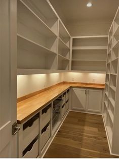 an empty kitchen with white cabinets and wood counter tops on both sides is lit by recessed lighting