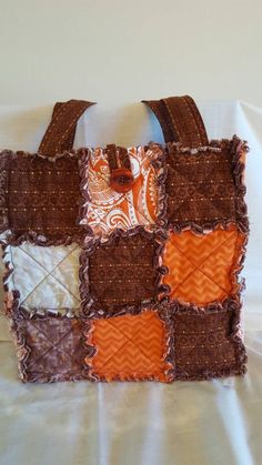 an orange and brown purse is sitting on a bed