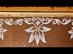 some white flowers painted on the side of a brown and yellow wall with an orange border