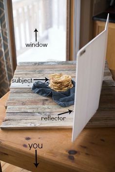 an open laptop computer sitting on top of a wooden table next to a stack of books