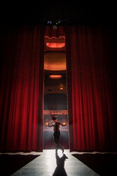 a person standing in front of a red curtain