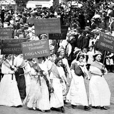 a group of women holding signs in front of a crowd