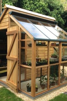 a small wooden greenhouse with lots of plants in it