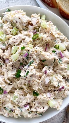 a white bowl filled with chicken salad next to bread