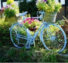 a white bicycle with flowers in baskets on the back wheel parked next to a house