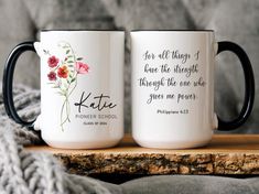 two coffee mugs sitting on top of a wooden table next to a gray blanket