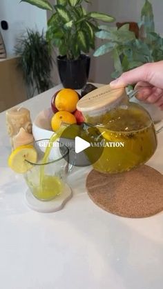 a person is pouring liquid into a bowl with lemons and oranges in it