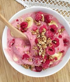 a bowl filled with ice cream and raspberries on top of a wooden table