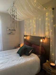 a bed with white sheets and lights on the headboard is in front of a window