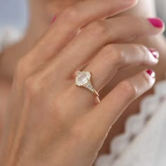 a woman's hand wearing a ring with a diamond in the middle and on top of her finger