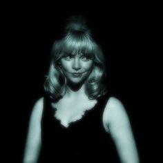 a black and white photo of a woman with long blonde hair wearing a black dress