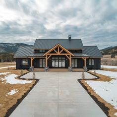 a large black house sitting in the middle of a snow covered field next to mountains