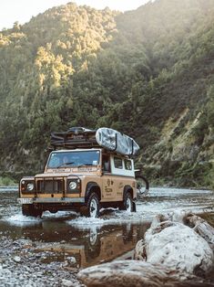 a jeep driving through a river with a tent on top