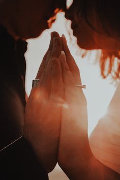 two people holding hands together with the sun shining through their eyes in the sky behind them