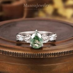 a close up of a ring with a green stone on it's middle finger