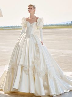 a woman in a white wedding dress standing on an airport tarmac