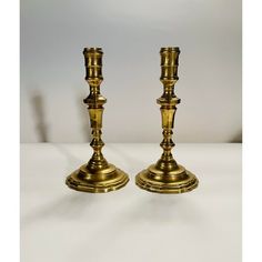 two brass candlesticks on a white table