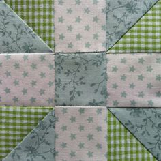 a green and white checkered patchwork quilt with stars in the center on it