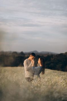 a man and woman are standing in the middle of an open field with tall grass