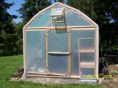 a small green house sitting on top of a lush green field