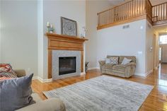 a living room with couches and a fireplace in the center, surrounded by hardwood floors