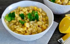 two white bowls filled with corn and garnished with parsley