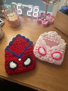 two crocheted cars sitting on top of a wooden table next to a clock