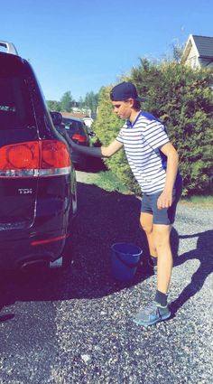 a man standing in front of a parked car next to a blue pailt