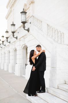 a man and woman standing on the steps in front of a white building with columns