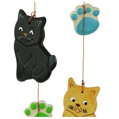 three ornaments with cats and paw prints hanging from strings