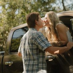 a young man and woman kissing in the back of a pickup truck while standing next to each other