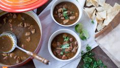 three bowls of chili with tortilla chips on the side