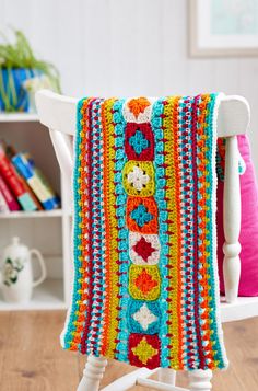 a white rocking chair with a colorful crocheted blanket on it's back