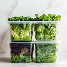 four plastic containers filled with green vegetables on a marble countertop next to a marble wall