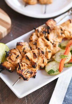 chicken skewers with vegetables and cucumbers on a white plate