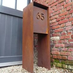 a metal mailbox sitting in front of a brick building with the number 55 on it