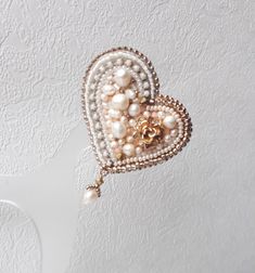 a heart shaped brooch with pearls attached to it's side and gold accents