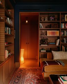 a living room filled with furniture and bookshelves next to a doorway that leads into a bedroom