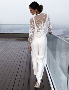 a woman standing on top of a wooden floor next to a glass wall and looking down at the ground