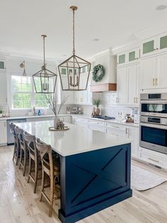 a kitchen with white cabinets and blue island