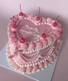 a pink heart shaped cake with candles on top