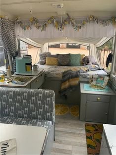 the inside of a camper that is decorated with yellow and gray accents, including curtains