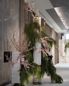 a tall vase filled with flowers and greenery on top of a white floor covered in snow