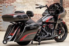 a black and red motorcycle parked next to a brick wall