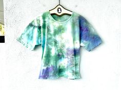 Vintage Hawaiian tshirt whimsically tie dyed with flowers blooming from the bottom up! S p e c i f i c s . . .  Label: --  Tagged Size: -- Approx. Fit: M - XL depending on fit pref Color: Greens // Purples // White Material: Soft perfectly worn in Cotton Tshirt Material  Condition: Overall in Amazing Vintage Condition (The best vintage not new but looks like you've owed this for years, condition) Hand Dyed Graphic Tee For Spring, Spring Graphic Tee Hand Dyed, Hippie Tie-dye Short Sleeve Tops, Hippie Tie Dye Short Sleeve Top, Hippie Hand Dyed Short Sleeve Tops, Spring Hippie Hand Dyed Tops, Tie Dye Hippie T-shirt For Spring, Spring Hippie Hand-dyed T-shirt, Artsy Design