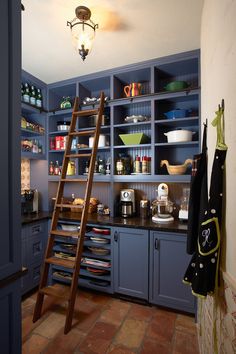 a ladder is in the middle of a kitchen with blue cupboards and other items