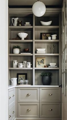 an open bookcase with white dishes on it