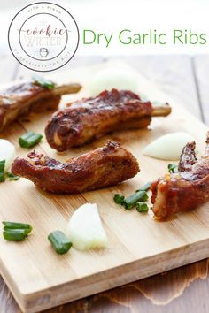 some meat is on a cutting board with onions and green herbs around it, as well as the words dry garlic ribs