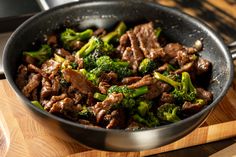 beef and broccoli in a skillet on a cutting board