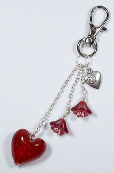 a red heart shaped keychain with three hearts hanging from it's side